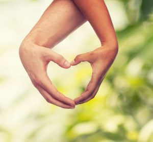 love and relationships concept - closeup of woman and man hands showing heart shape