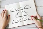 Pessoa desenhando nuvens em um caderno.