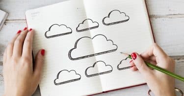 Pessoa desenhando nuvens em um caderno.