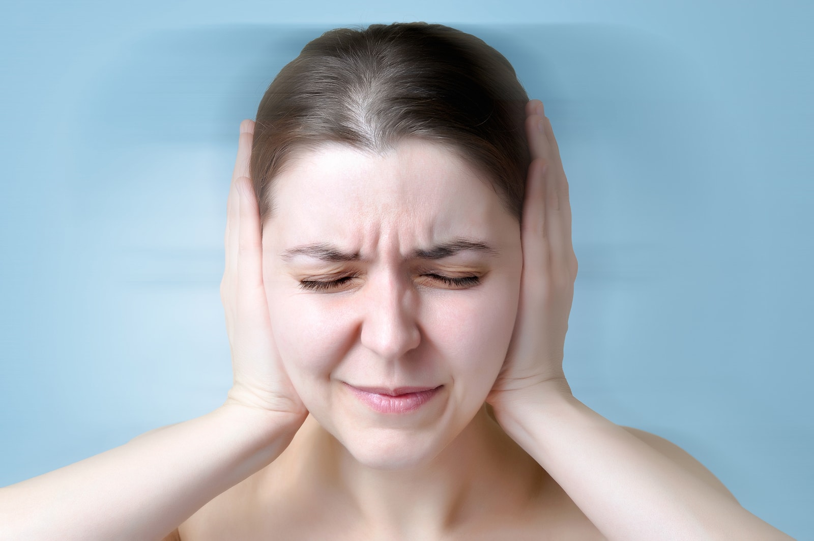 A young woman suffering from noise and covering her ears