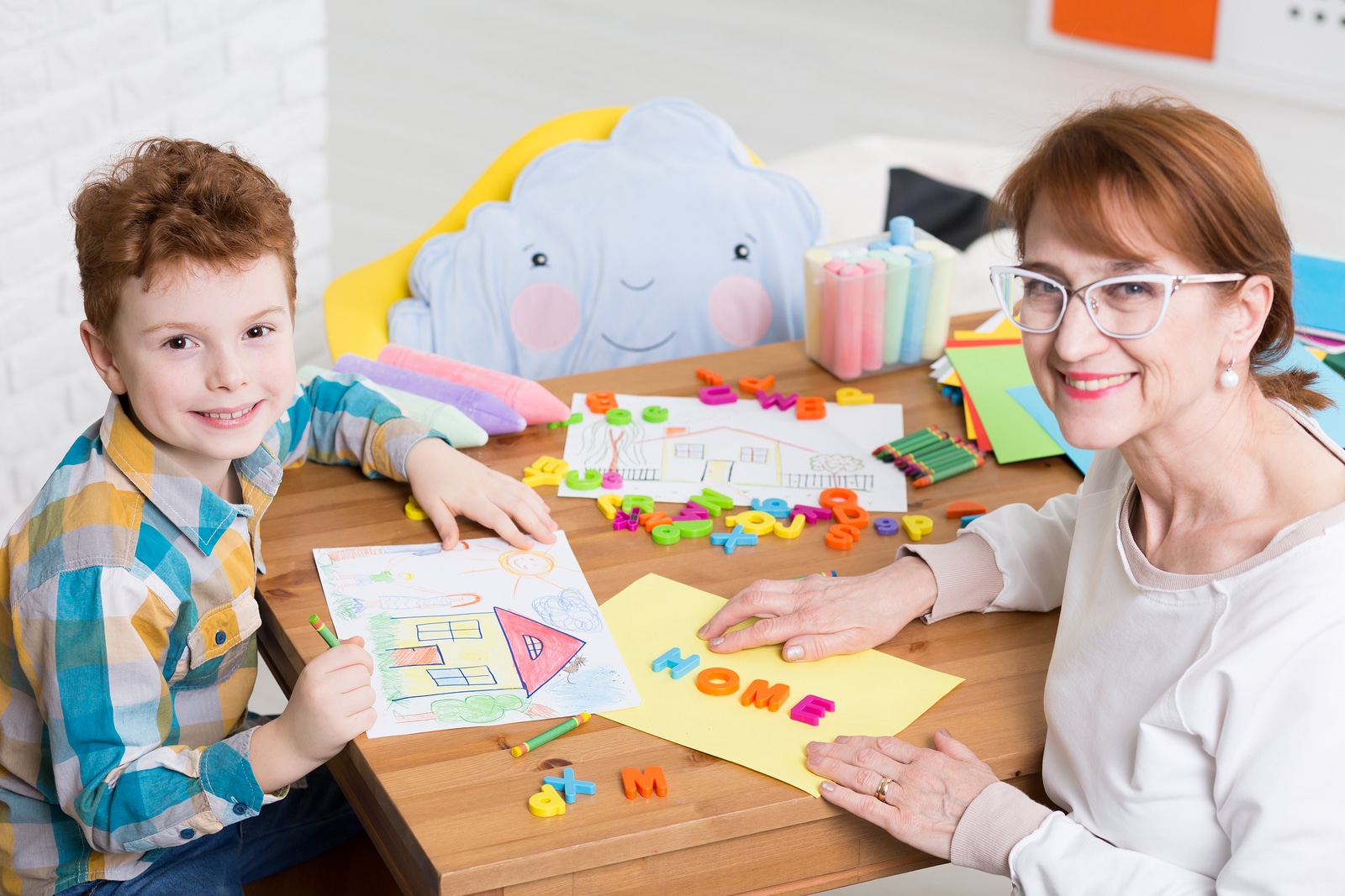 Nice smiling occupational therapist working with little boy with adhd. Teaching the kid new words