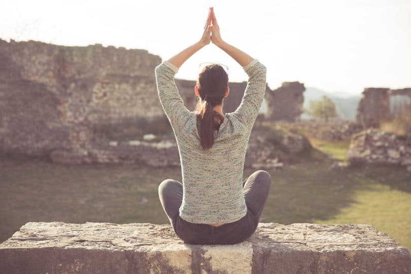 Yoga and meditation concept.Woman meditating in sitting yoga position outdoors.Woman alone practicing mindfulness meditation to clear her mind.Zen,meditation,peace concept