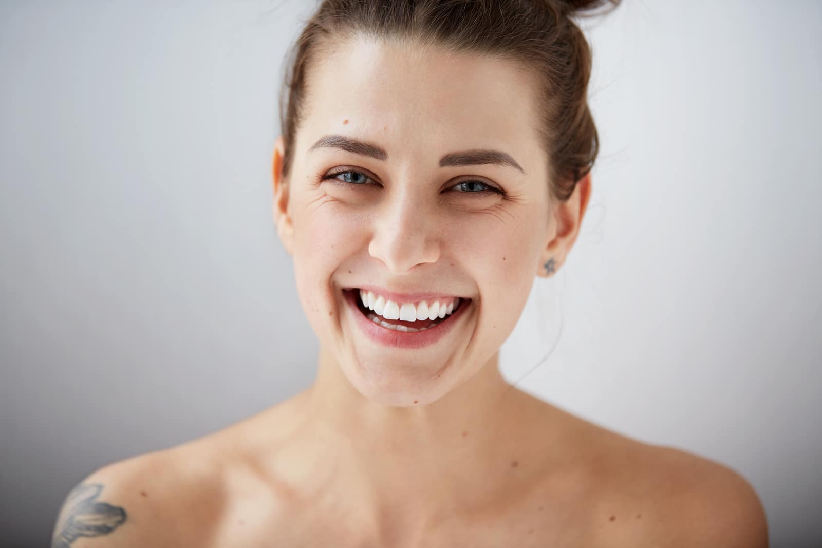 Beauty girl face Portrait. Beautiful model woman perfect fresh clean skin. Female looking at camera and smiling. Youth and skin care concept. Isolated on background