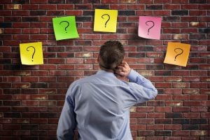 Choice and decisions: businessman thinking with question marks w