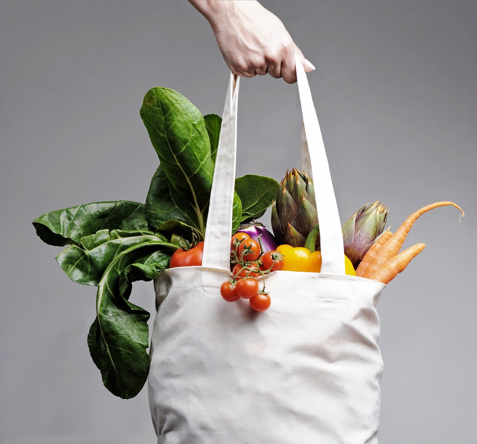 full of vegatables cotton shopping bag carried by a human hand