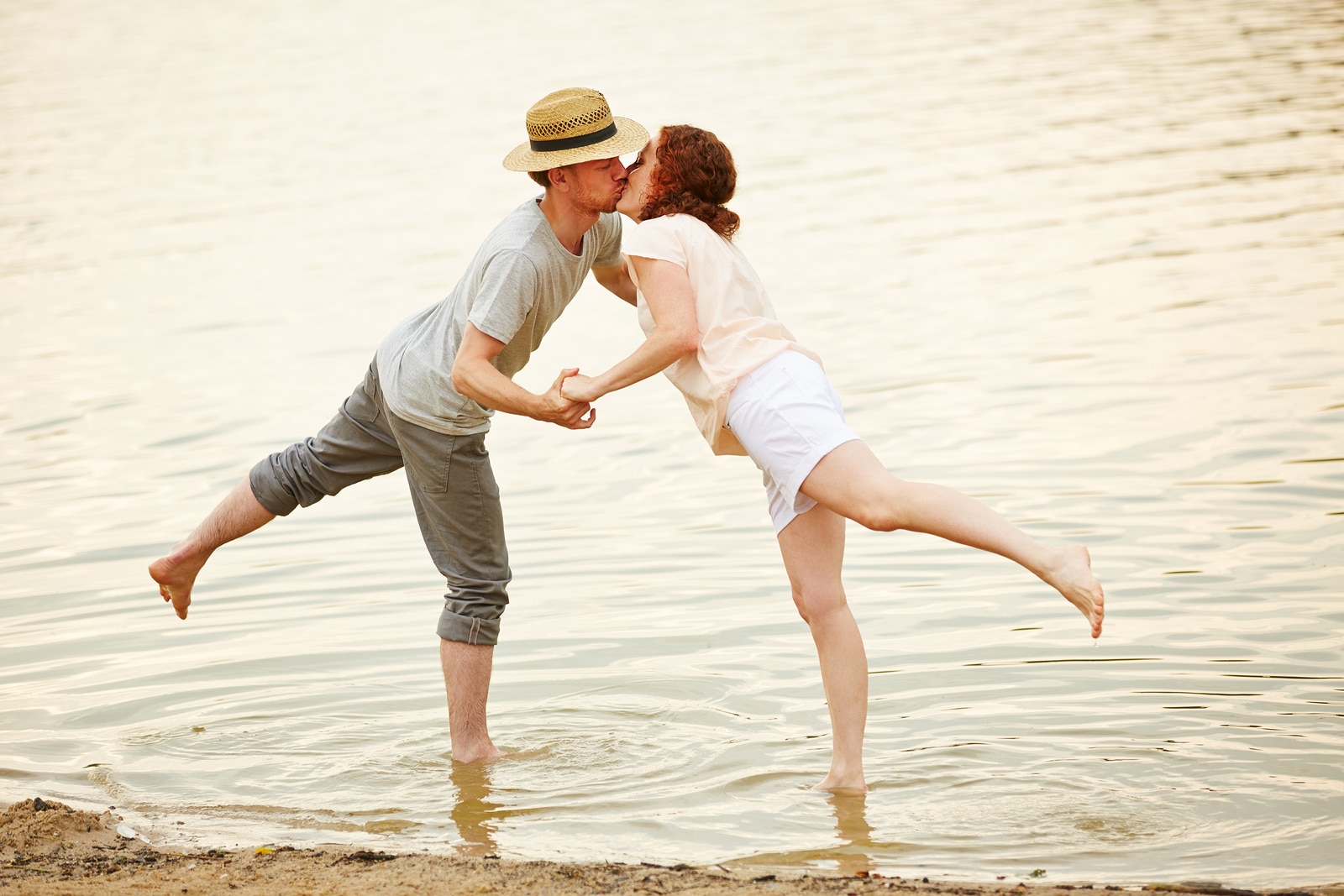 Couple in love kissing in water of lake in summer