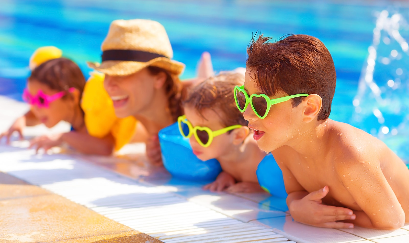 Happy family in the pool, having fun in the water, mother with t