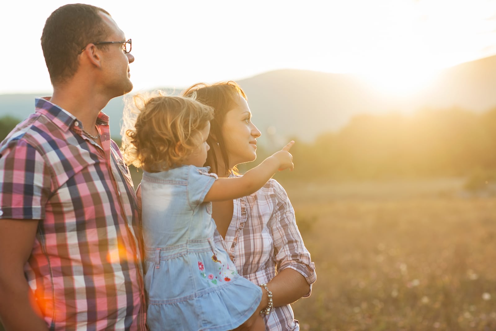 Happy family having fun outdoors and smiling. They are on the field, the last rays of the sun.