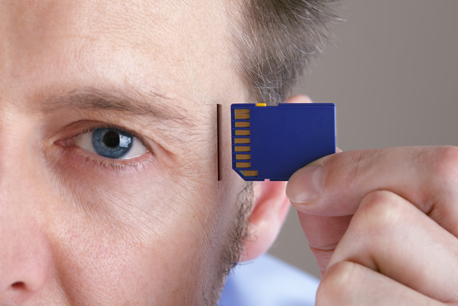 Inserting SD memory card into slot in human head concept for memory upgrade, forgetfulness or computing
