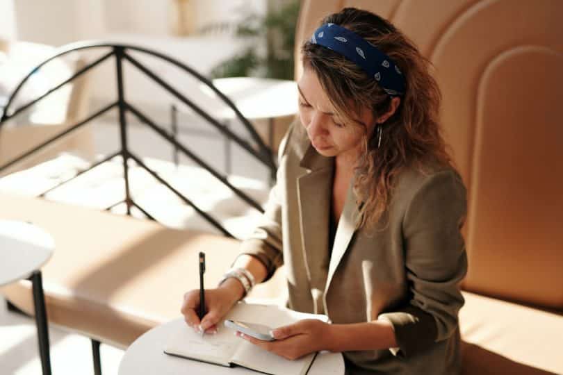 Mulher escrevendo em um caderno em um escritório