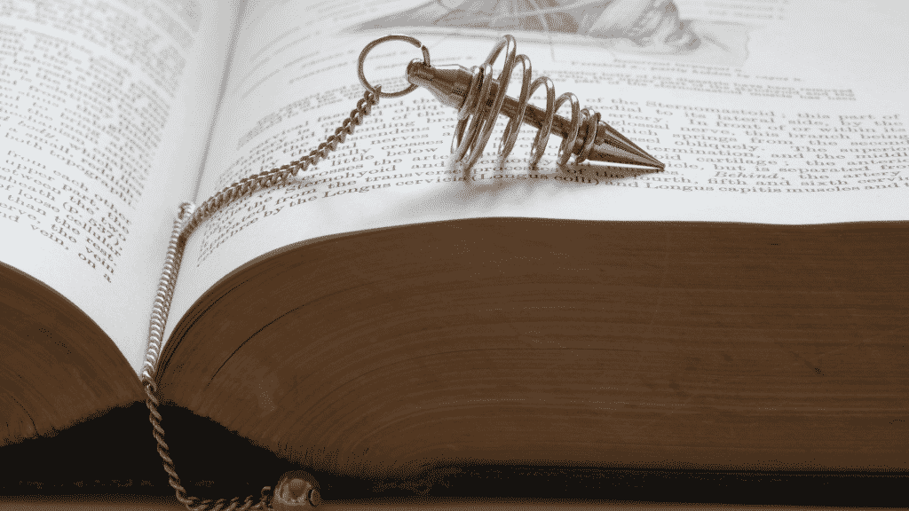 Pêndulo de radiestesia sobre um livro aberto