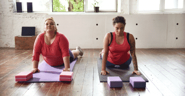 Duas mulheres em uma sala praticando yoga no chão