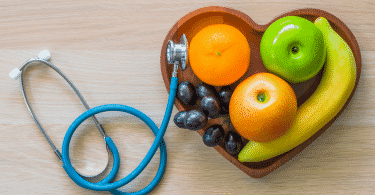 Imagem de frutas em um recipiente em formato de coração. Ao lado, um estetoscópio.