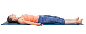 Beautiful sporty fit yogini woman relaxes in yoga asana Savasana - corpse pose in studio