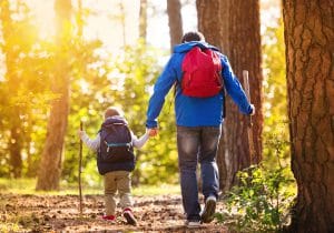 Father and son walking during the hiking activities in autumn forest at sunset