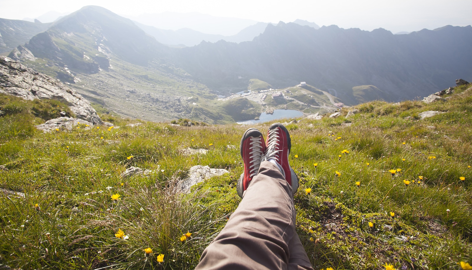 Legs of traveler sitting on a high mountain top in travel. Freedom concept