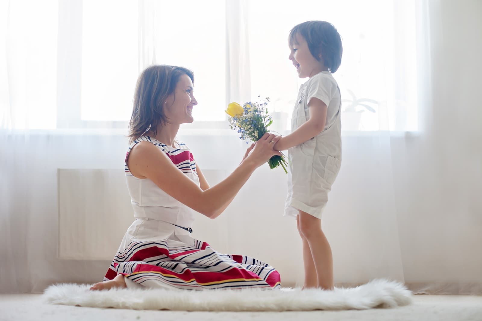 Mother and her child embracing with tenderness and care child giving mother flowers. Mother day concept happiness and love