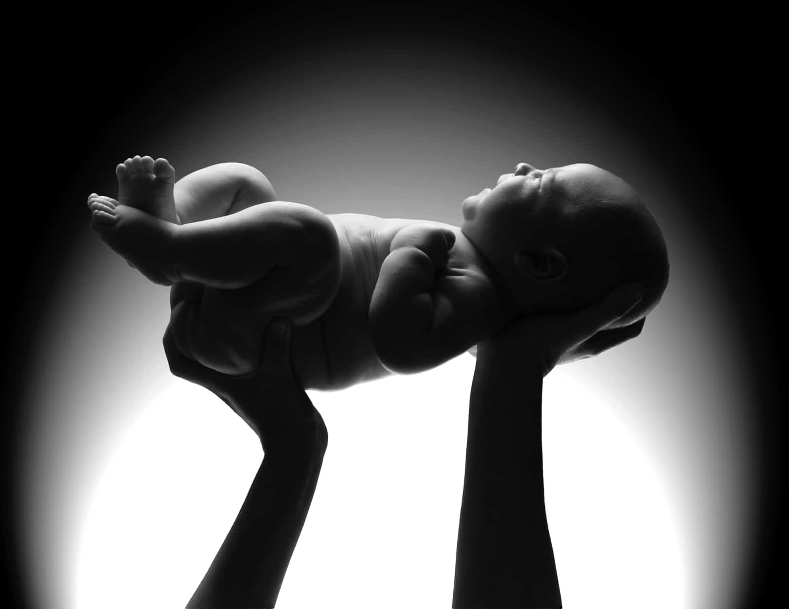 Mother's hands holding a newborn baby.