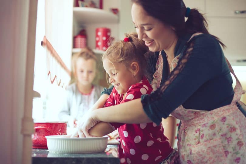 Mother with her 5 years old kids cooking holiday pie in the kitchen to Mothers day, casual lifestyle photo series in real life interior