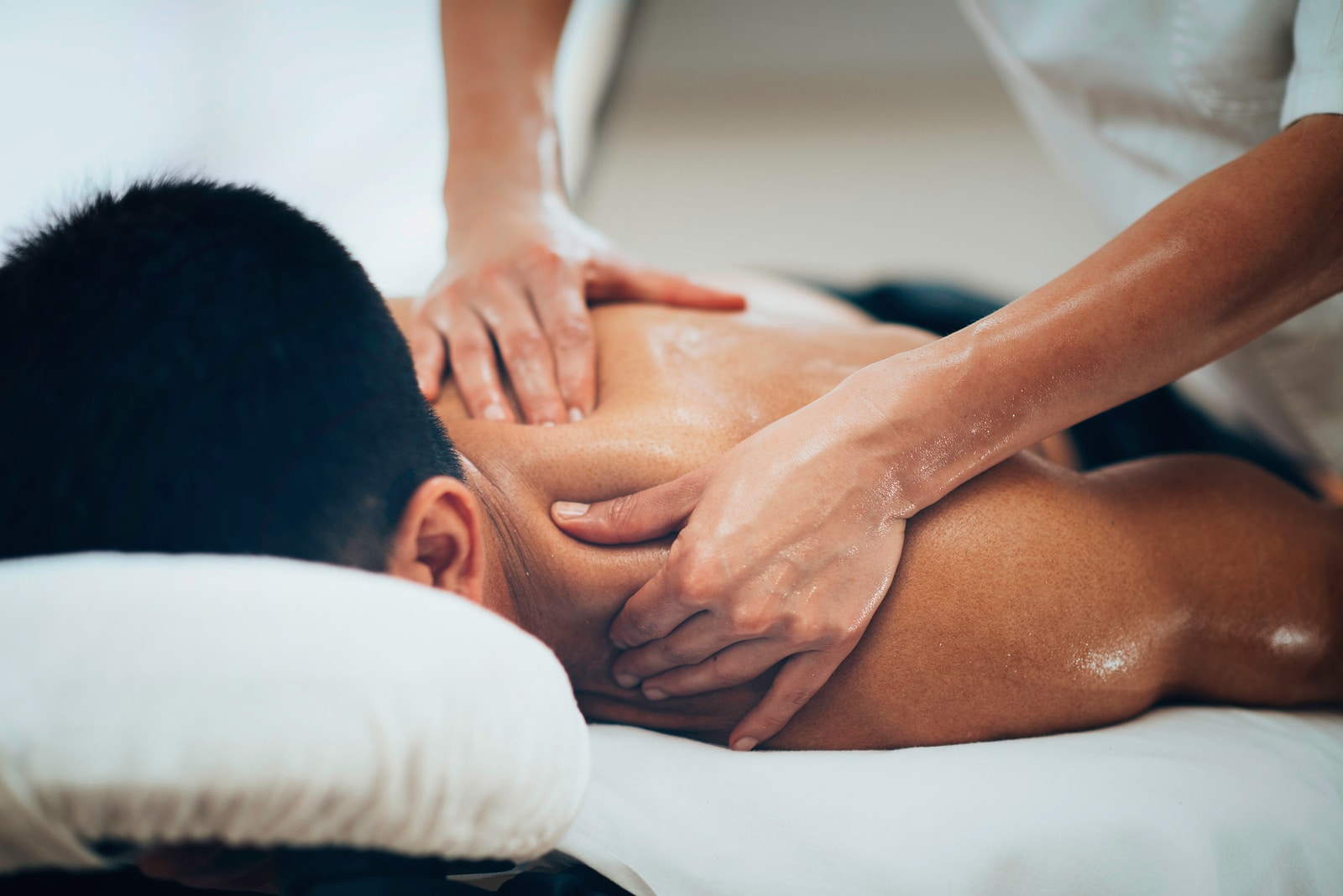 Massage therapist applying strong finger pressure to shoulder muscles