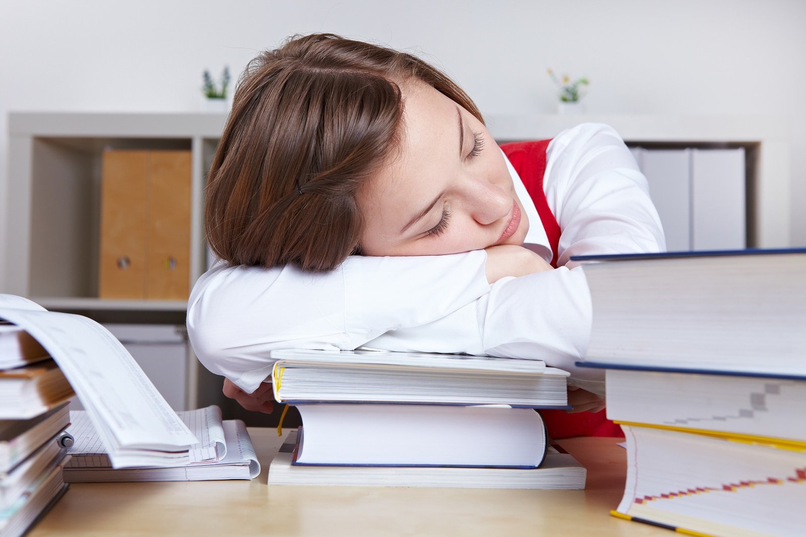 Tired woman sleeping on books after studying for exams