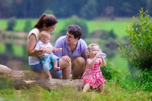 Family on summer hike. Young parents with kids hiking next to a lake. Mother father and two children having picnic outdoors. Active trekking with baby and toddler. Beautiful nature of Germany.