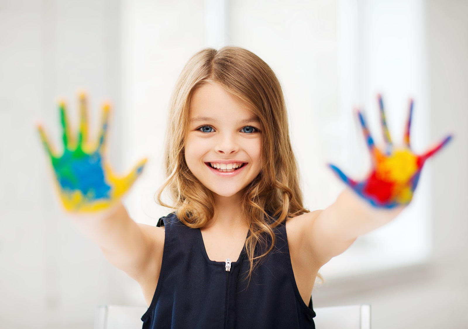 education, school, art and painitng concept - little student girl showing painted hands at school