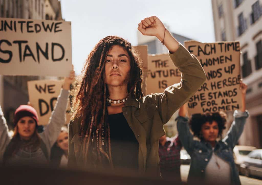 Mulher em protesto segurando cartazes