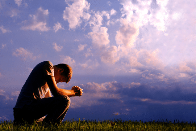 Homem agachado e rezando