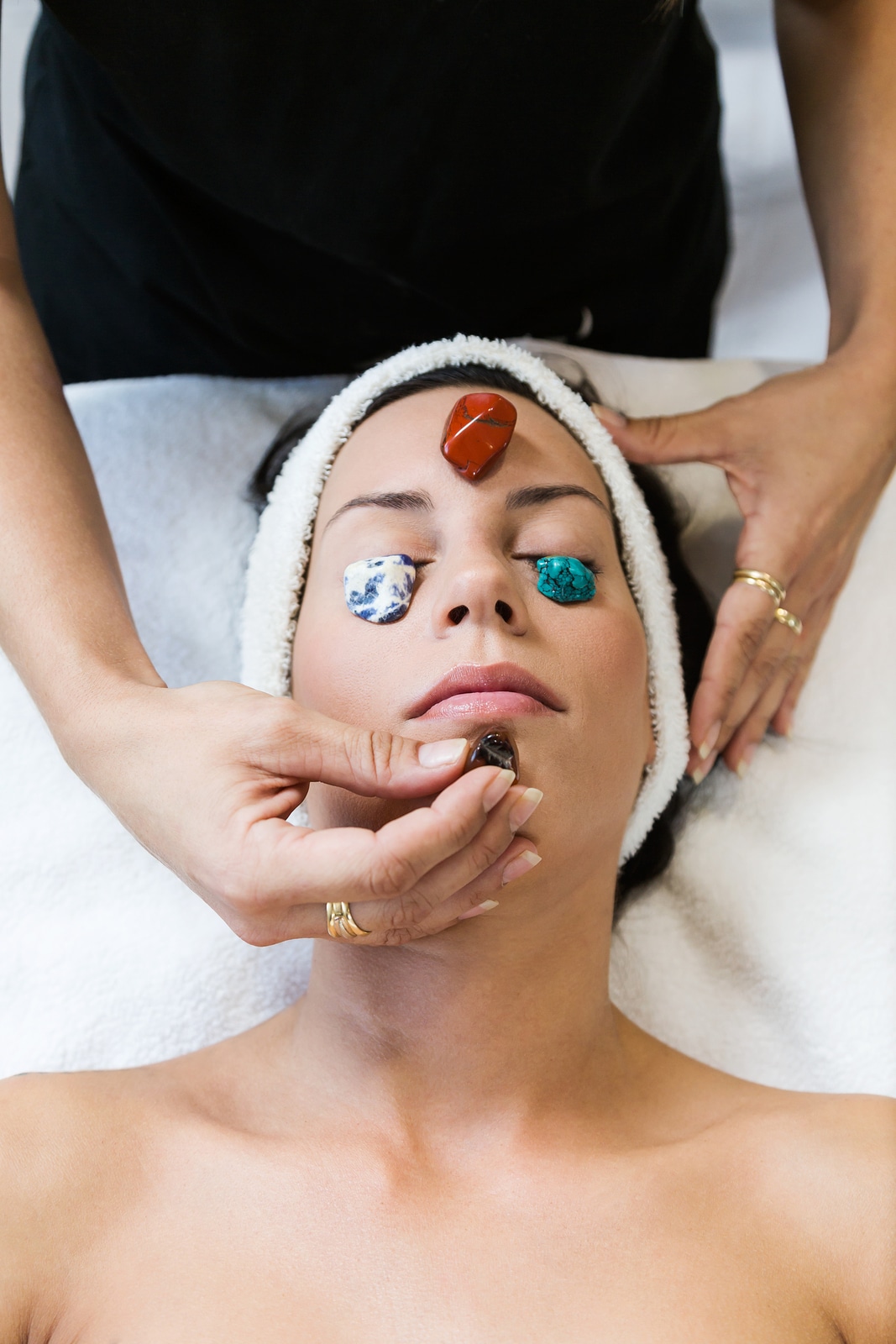 Portrait of beautiful young woman receiving gemstone therapy in spa.