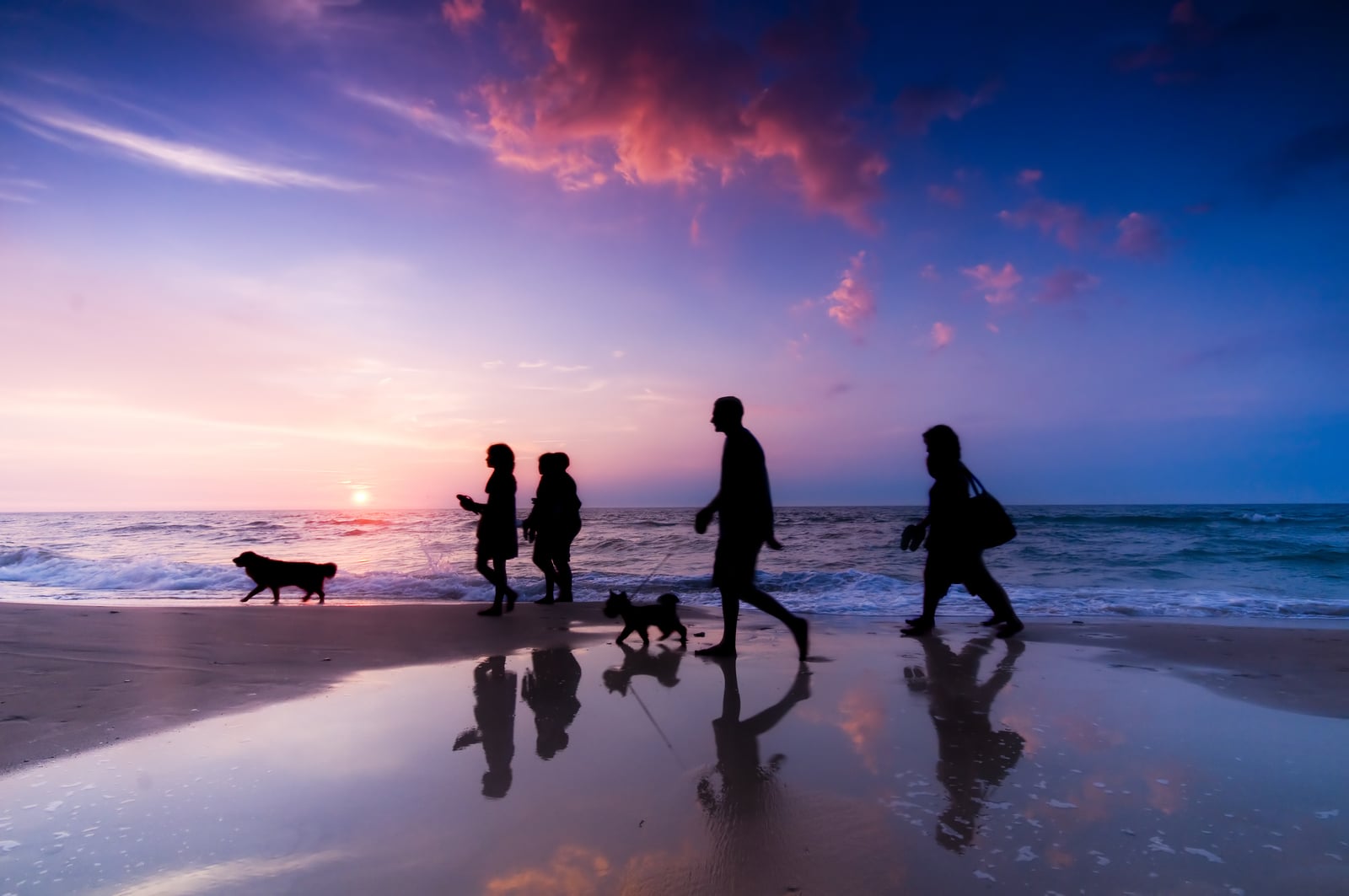 Family walk on the beach at sunset