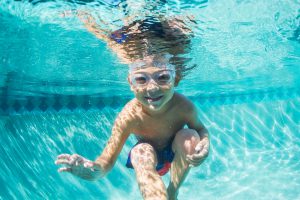 Underwater Young Boy Fun in the Swimming Pool with Goggles. Summer Vacation Fun.