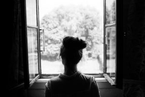 Woman looking through the old window on the garden or forest in the countryside. Black and white photography. Fairy tail motive.