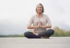 Mulher mais velha sentada em pose de meditação.