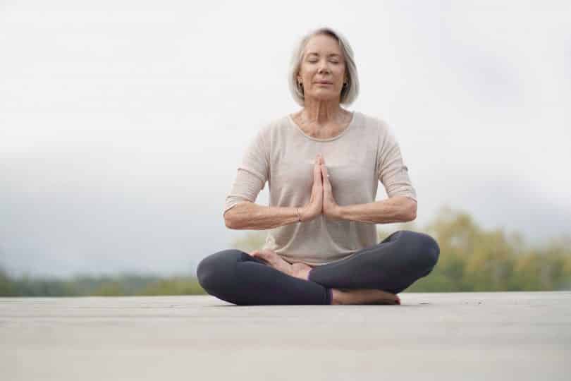 Mulher mais velha sentada em pose de meditação.