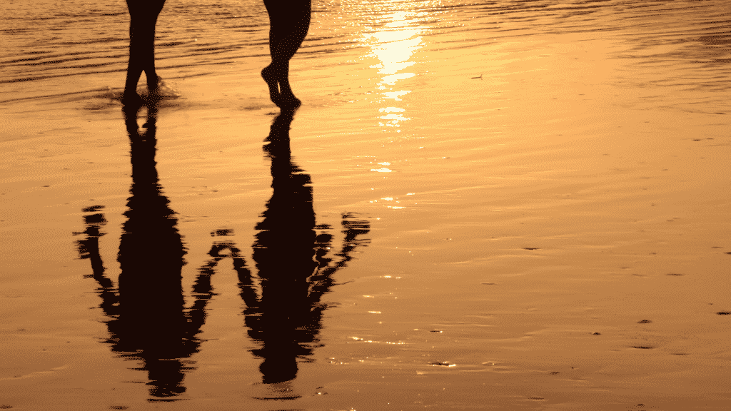 Silhueta de casal caminhando de mãos dadas na praia