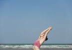 Mulher na praia de top com braços unido no alto meditando