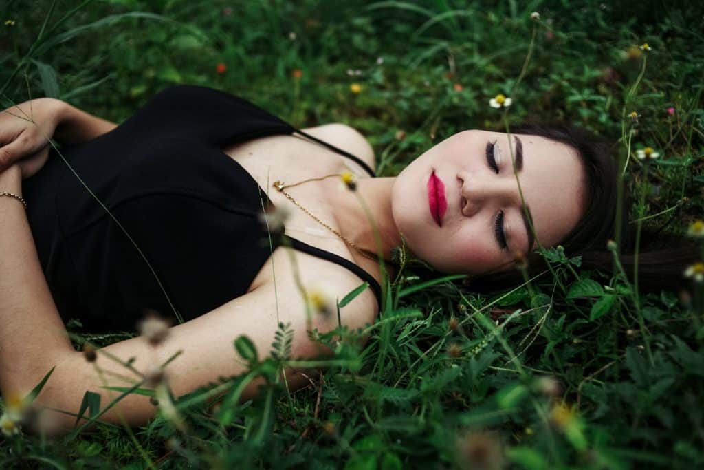 Mulher deitado em um gramado de olhos fechados