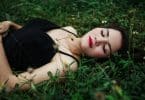 Mulher deitada em um gramado de olhos fechados