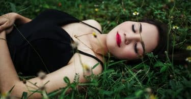 Mulher deitada em um gramado de olhos fechados