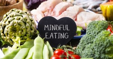 Bancada com carnes e legumes e uma plaquinha preta escrito "mindful eating".