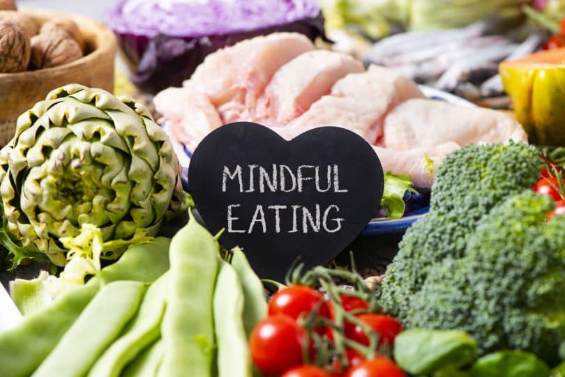 Bancada com carnes e legumes e uma plaquinha preta escrito "mindful eating".