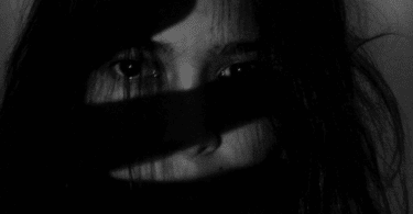 foto em preto e branco de uma mulher com feição de medo.