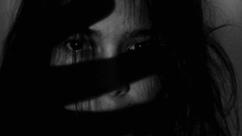 foto em preto e branco de uma mulher com feição de medo.