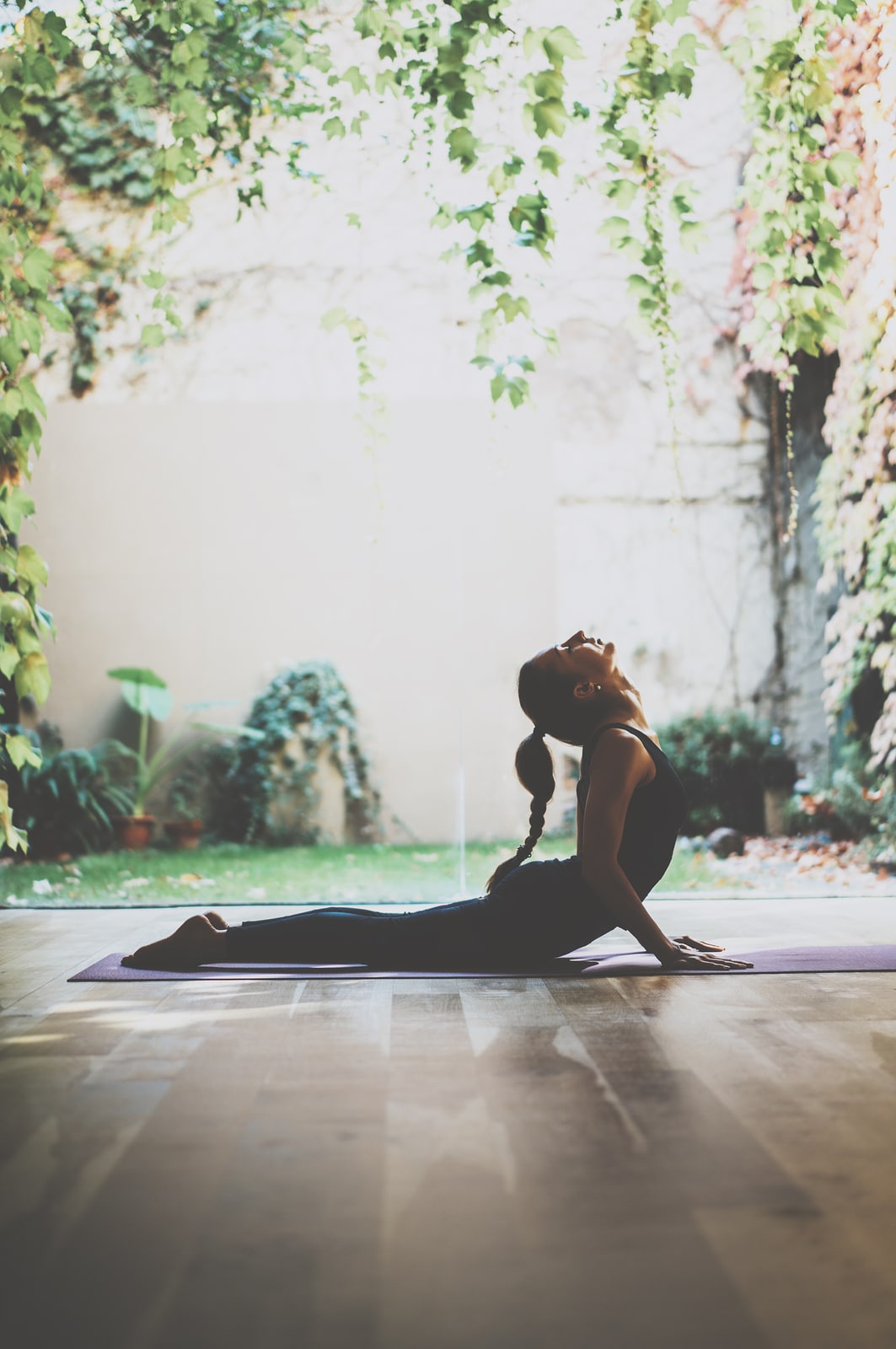 Portrait of gorgeous young woman practicing yoga indoor. Beautiful girl practice cobra asana in class.Calmness and relax, female happiness.Vertical, blurred background