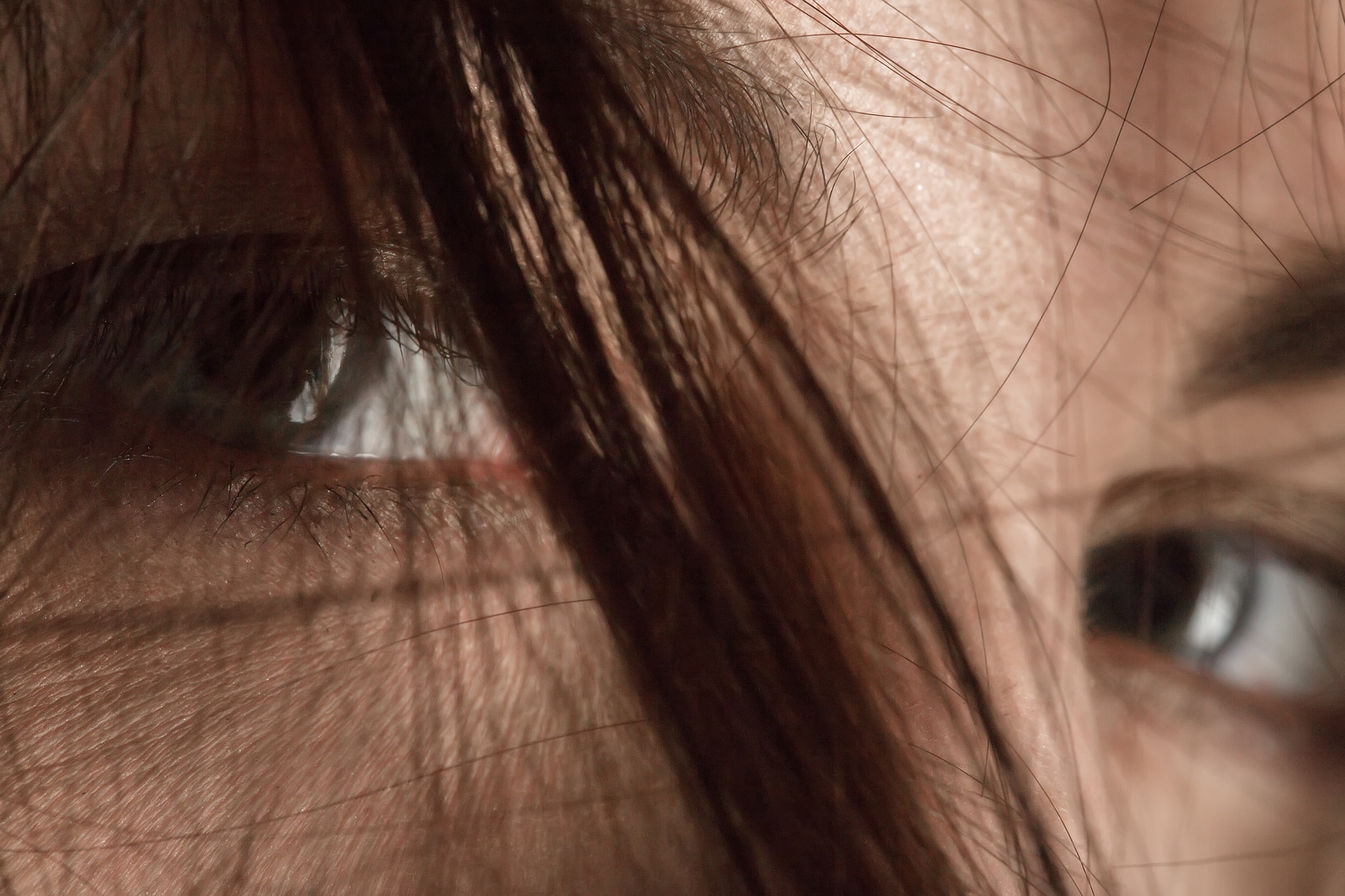 sad female eyes under blowing hair close up macro image