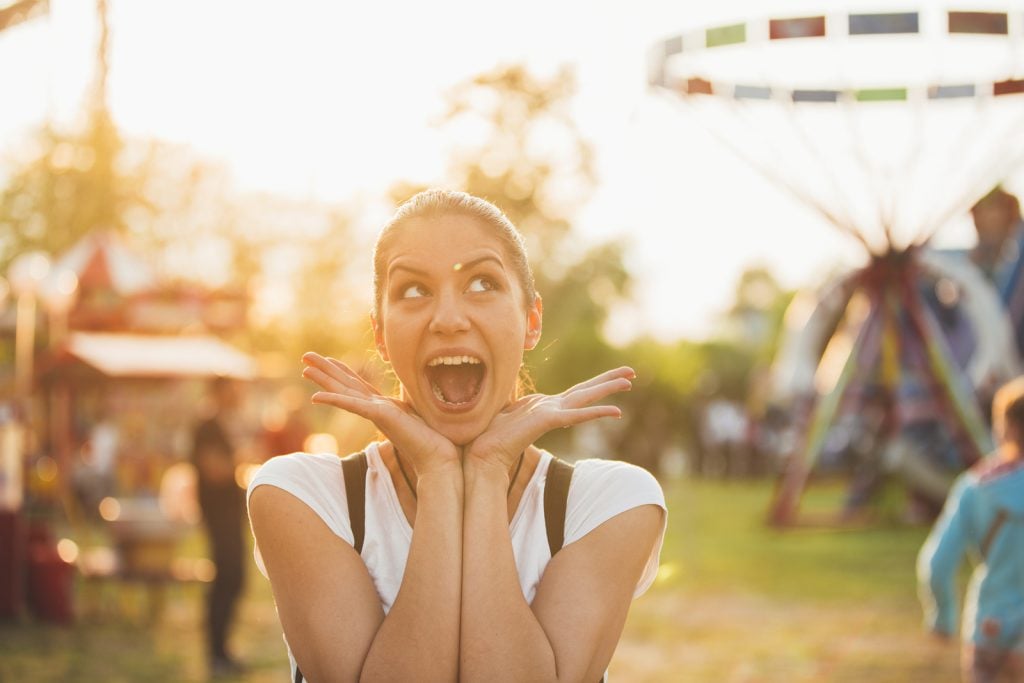 Young woman in a good mood.Enjoying in life concept.Happiness. Having fun at funfair.Spending time in a amusement park,summer vacation with friends.Colorful and inspirational.Very excited girl