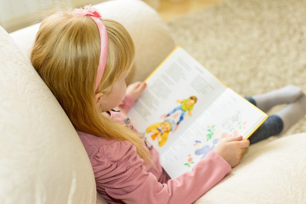 a girl reading a book sitting in a chair