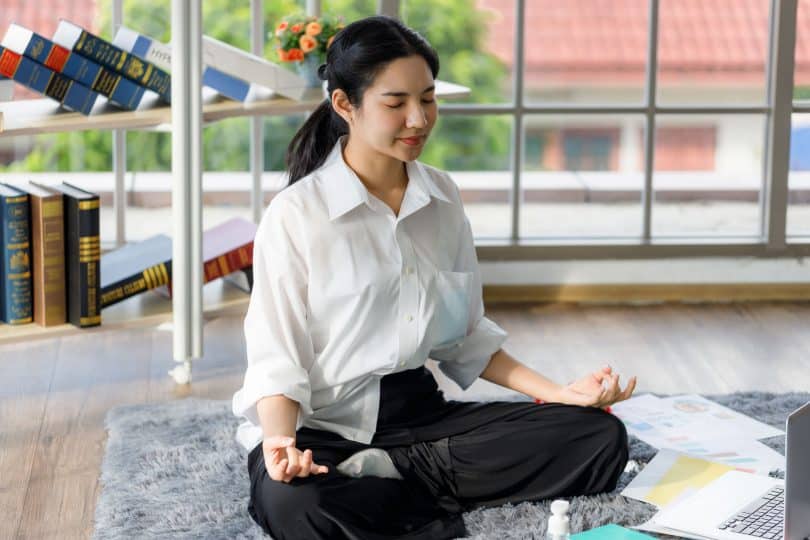 Garota chinesa meditando na sala de casa.