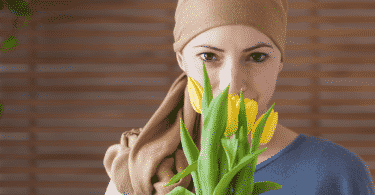 Mulher com um pano enrolado n a cabeça segurando um buquê de tulipas amarelas